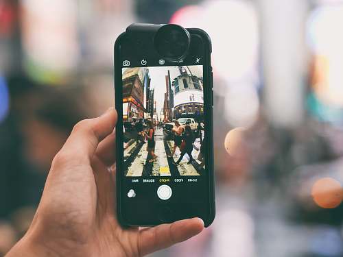iphone tilt-shift lens photography of smartphone captured fish-eye lens photograph photo of people crossing on pedestrian lane cell phone